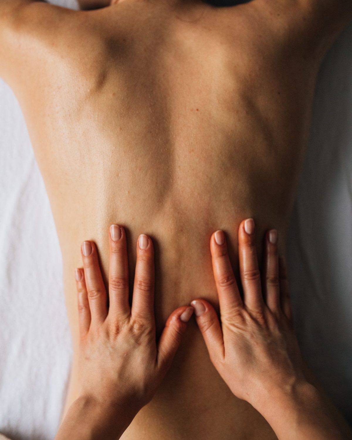 A therapist's hands working across a client's back
